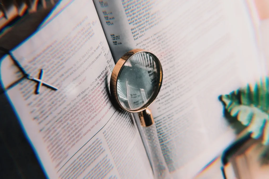 An open Bible with a magnifying glass and a small cross
