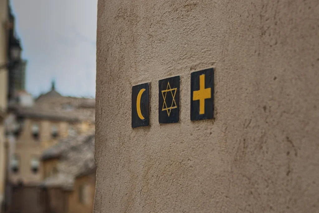 Symbols of Islam, Judaism, and Christianity displayed side by side on a stone wall